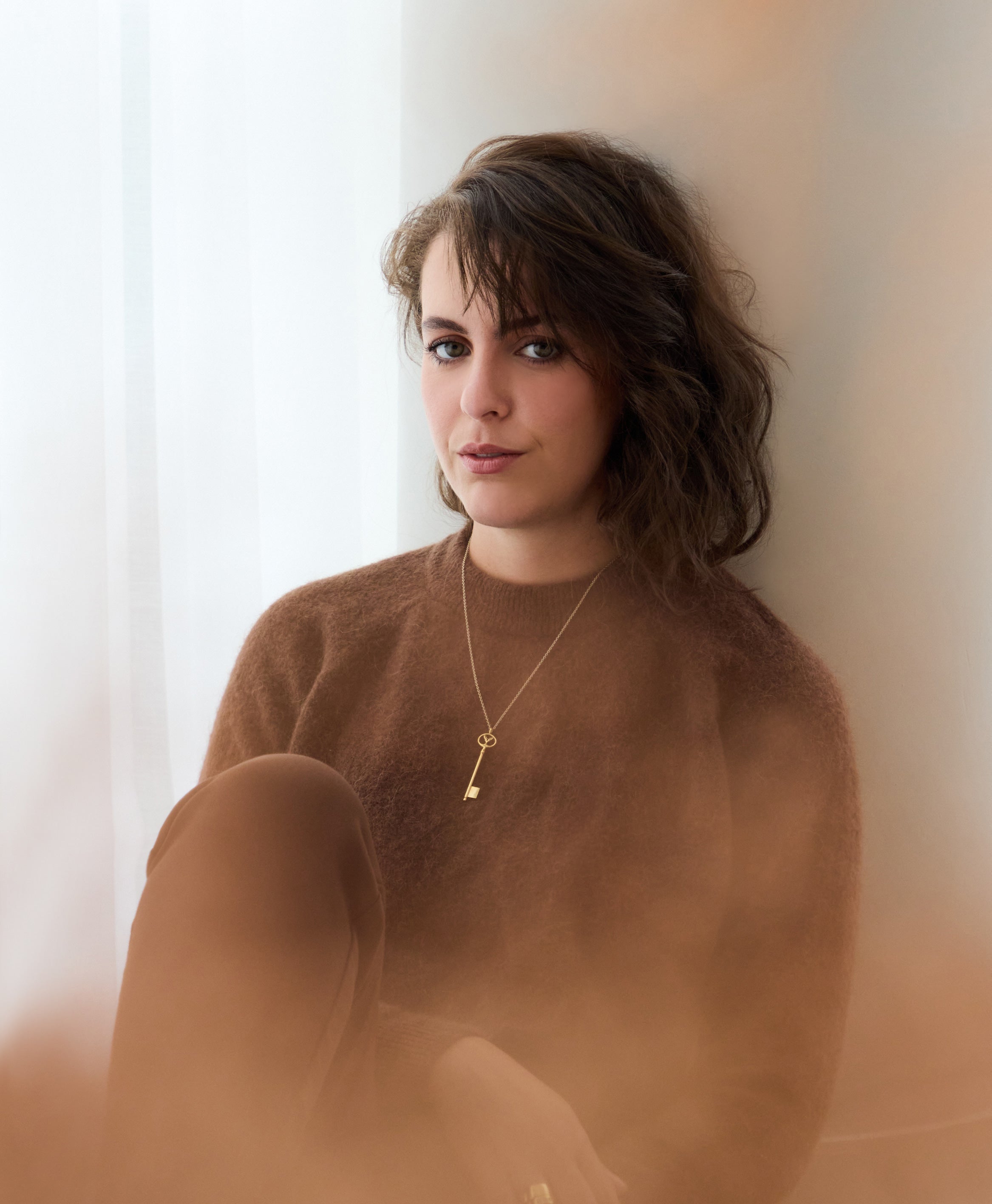 Alicia Djouab, founder GROUPE DEMONT INC, portrait assise avec tenue marron et pendentif du club intellectuel montréal.
