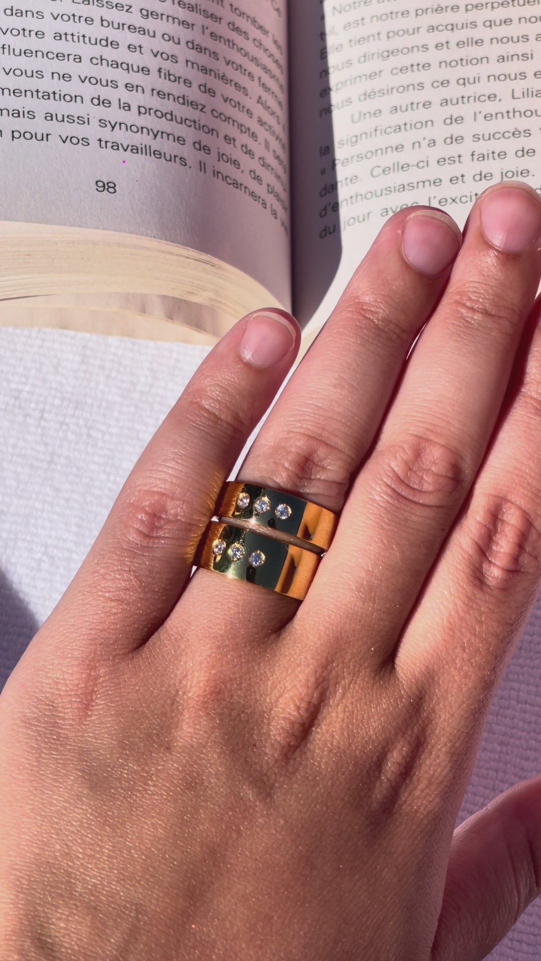 close up video of DOLCE rings worn by a hand model reading a book in montreal by the pool in summer.